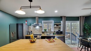 A modern kitchen with a wooden island, stainless steel appliances, and a view to the outside. - NEW Lodge•HotTub.Game Room.Firepit.Theater.Hammocks (Tobyhanna)