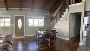A spacious living area with hardwood floors, a dining table with chairs, a chandelier, and a staircase leading to another level. - Family Friendly Lakehouse with great views! (Jasper)
