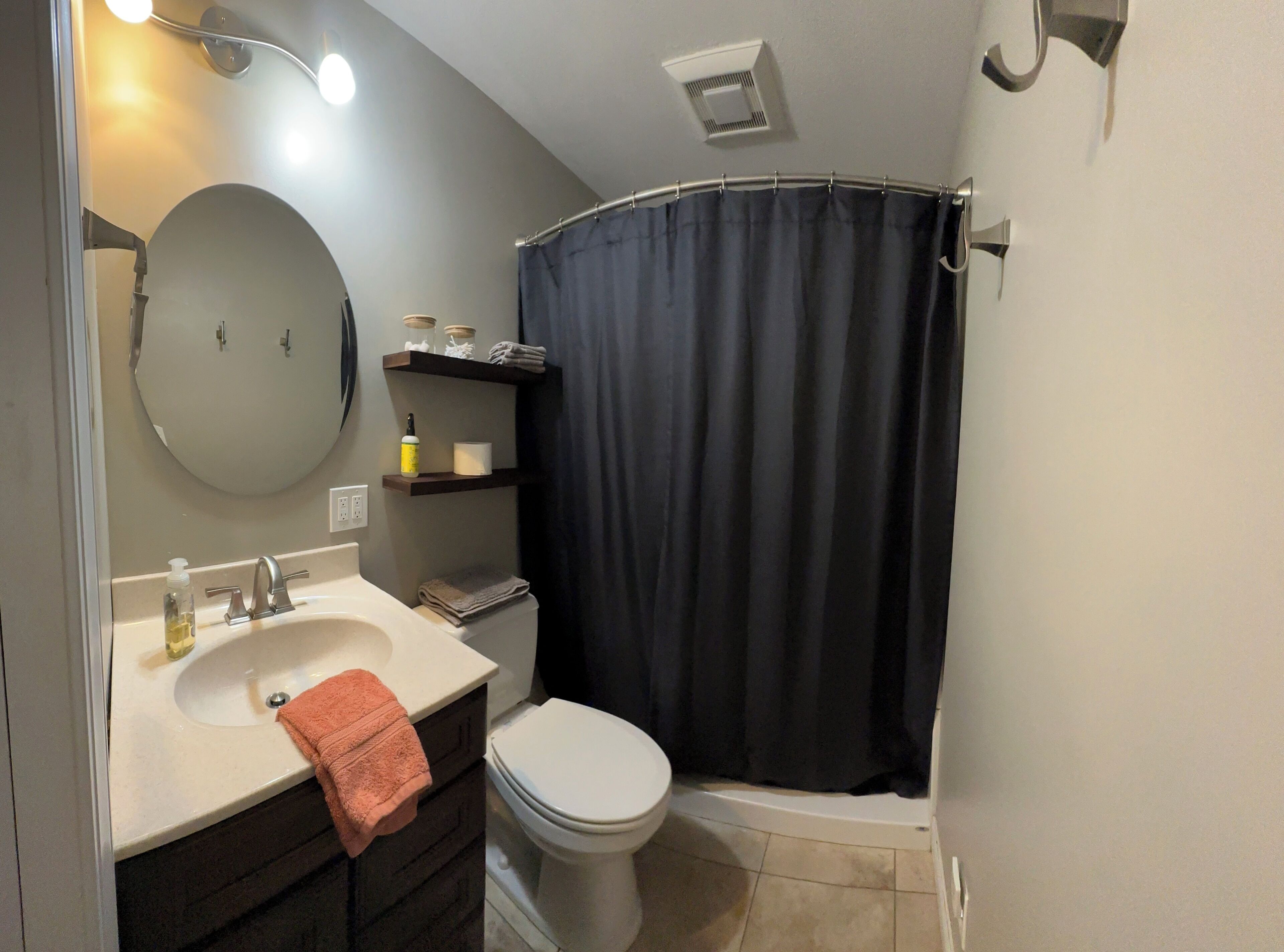 Un baño con lavamanos, espejo, inodoro y cortina de ducha.
