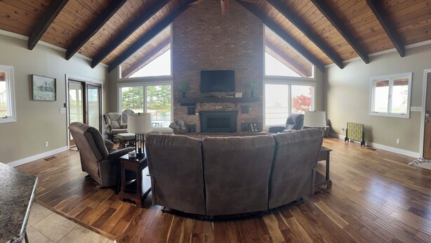 A spacious living room with a fireplace, a large window, and a high ceiling with exposed beams. - Family Friendly Lakehouse with great views! (Jasper)