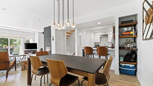 A modern dining area with a dark wooden table and matching chairs, a hanging light fixture, and a view of the kitchen and living space. - Modern 3 Bed / 3 Bath Townhome in Vail with Private Garage - Pets Welcome! (Vail)