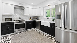 A modern kitchen with white cabinets, a stainless steel refrigerator, a microwave, and a stove. - Modern 3 Bed / 3 Bath Townhome in Vail with Private Garage - Pets Welcome! (Vail)