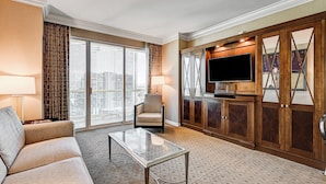 Un salon d’hôtel comprenant un canapé, un fauteuil, une télévision et des meubles en bois.