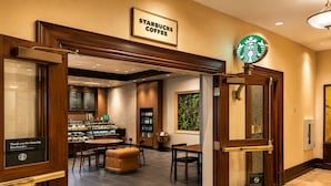 Un café Starbucks avec un comptoir, un espace salon et une grande fenêtre ornée d’un tableau.