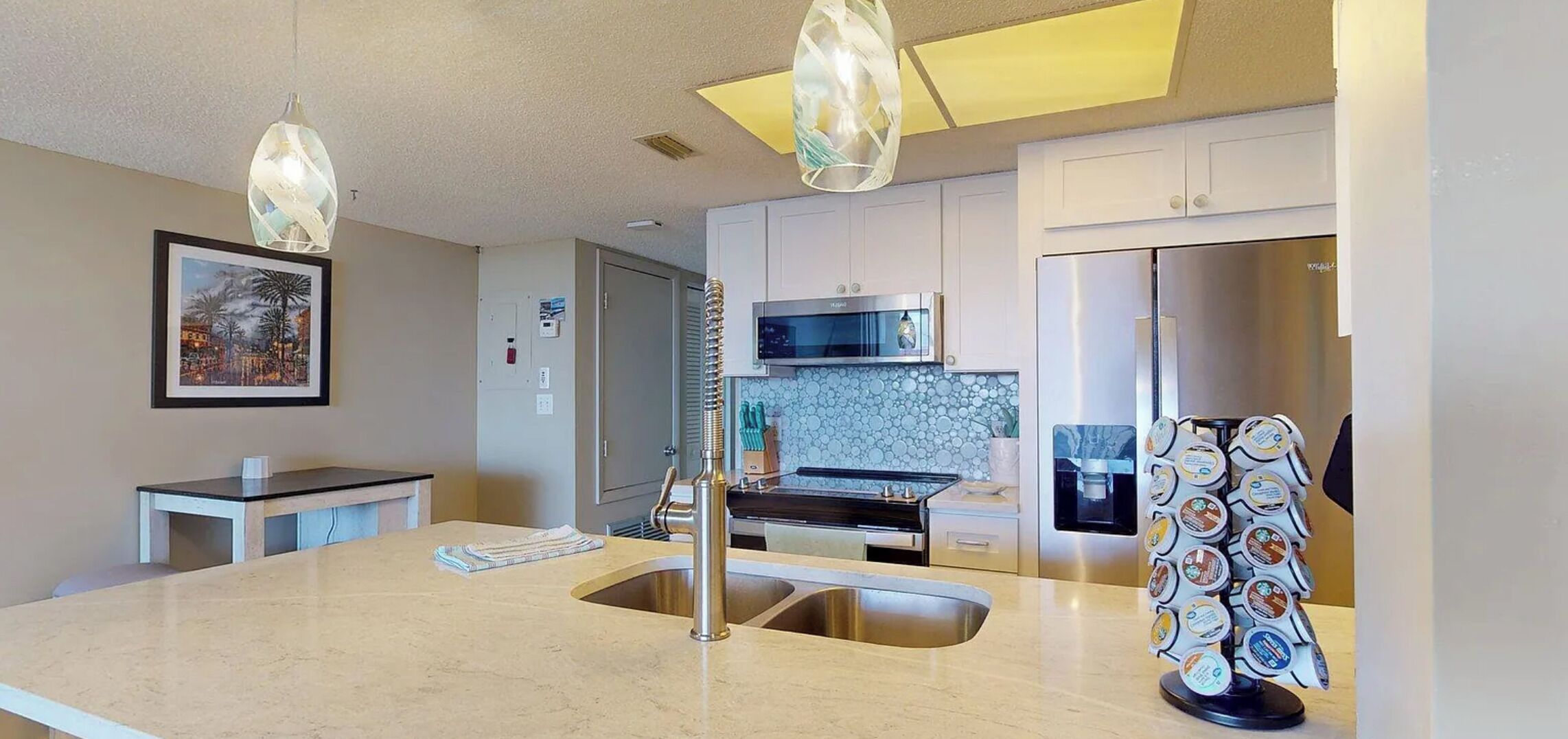 Una cocina moderna con una isla central, electrodomésticos de acero inoxidable e iluminación colgante.