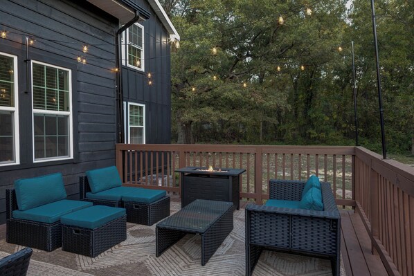 A deck with outdoor furniture, a fire pit, and string lights. - Modern and Peaceful 5BR Wake Forest Retreat-Pet Friendly (Wake Forest)