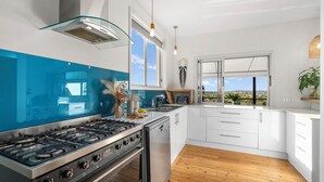 A modern kitchen with a gas stove, oven, and white cabinets. - Riverside Retreat with Sweeping Views – Pool, Guest Suite & Entertainers Balcony (Tweed Heads)