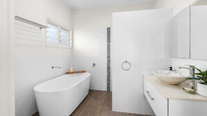 A modern bathroom with a freestanding bathtub, a vanity with a bowl sink, and a shower area. - Riverside Retreat with Sweeping Views – Pool, Guest Suite & Entertainers Balcony (Tweed Heads)
