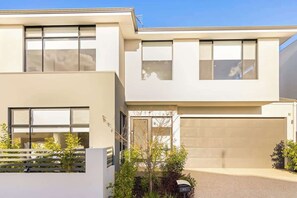 Una moderna casa a due piani con ampie finestre, un garage e un giardino curato.
