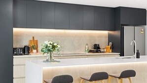 Cozinha moderna com ilha central, banquetas e forno embutido.