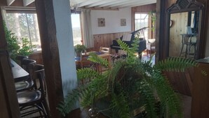 Een gezellige kamer met een piano, houten meubels en een grote varen.