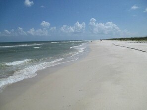 A wide sandy beach with gentle waves, a clear sky, and a distant horizon. - Quads-For-Fun, Units 1-4, Saint George Island, FL (Eastpoint)