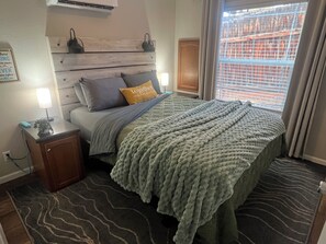 A bedroom with a bed, bedside lamps, a nightstand, and a window with blinds. - Cozy Fall Retreat - Pikes Peak Views + Walkable (Woodland Park)