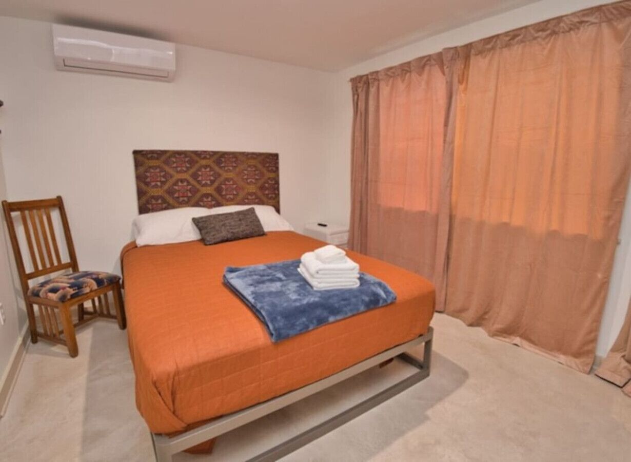 A bedroom with a bed, a chair, a blanket, and a pillow.