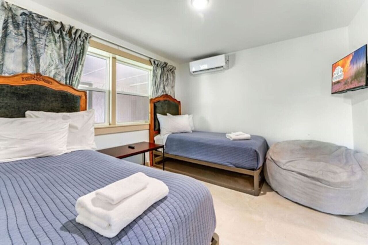 Ein Hotelzimmer mit zwei Betten, einem kleinen Tisch, einer Klimaanlage und einem Sitzsack.