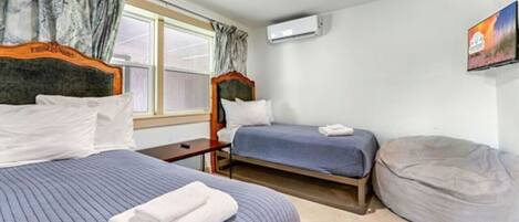 Ein Hotelzimmer mit zwei Betten, einem kleinen Tisch, einer Klimaanlage und einem Sitzsack.