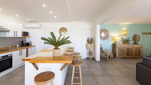 A modern kitchen with white cabinets, a wooden island with stools, a microwave, and a coffee maker.