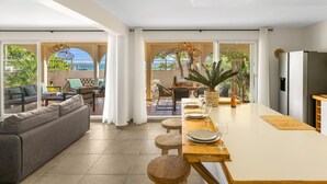 A modern kitchen with a dining area, large windows, and a view of the outdoors.