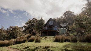 Una casa moderna con una amplia terraza, rodeada de vegetación y árboles nativos.