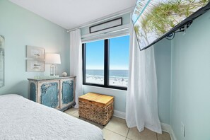 Ein Schlafzimmer mit Bett, Schminktisch, Fenster mit Blick auf den Strand und einer kleinen Holzschatulle.