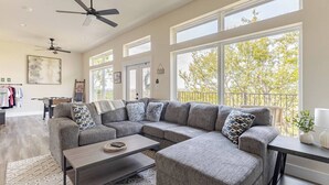 Ein geräumiges Wohnzimmer mit einem großen Ecksofa, einem Couchtisch und einem Balkon mit Blick auf Bäume.