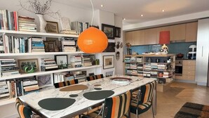 Ein modernes Wohnzimmer mit einem Marmortisch, gestreiften Stühlen und einer Bücherwand voller Bücher und Dekoration.
