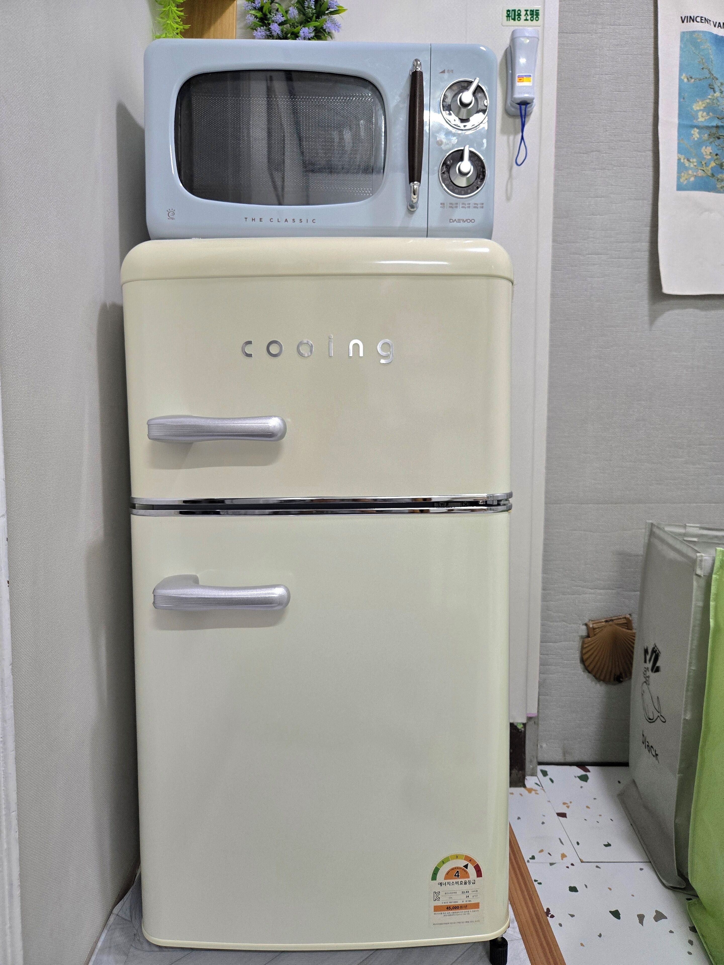 A vintage two-door refrigerator with a microwave on top, a handle on each door, and a sticker indicating a 4-star rating.