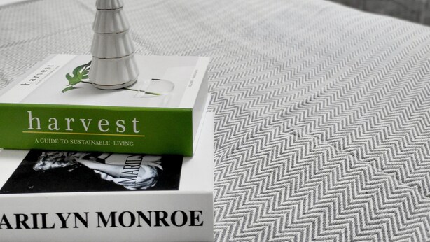 A neatly made bed with a green book titled 'harvest' by Marilyn Monroe on it. - Moon Stay (Seoul)