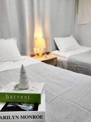 A neatly made bed with a green book titled 'harvest' by Marilyn Monroe on it. - Moon Stay (Seoul)