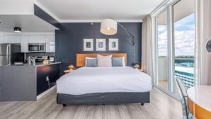 Ein modernes Hotelzimmer mit einem großen Bett, einer Küchenzeile und einem Balkon mit Blick.