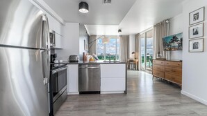 Eine moderne Küche mit Edelstahlgeräten, einer zentralen Kochinsel und Blick auf die Stadt durch große Fenster.