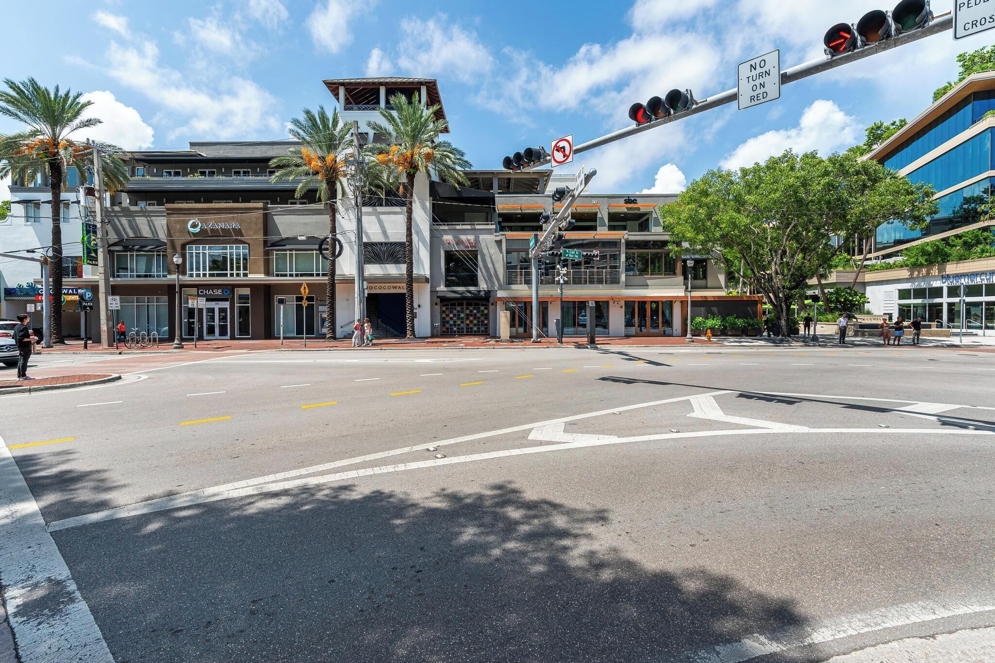 A modern building with a prominent entrance, a pedestrian crossing, and a traffic light.