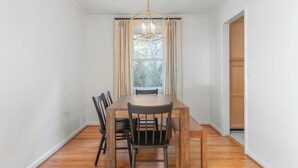 Ein Esszimmer mit Holztisch, Stühlen und einer Pendelleuchte.