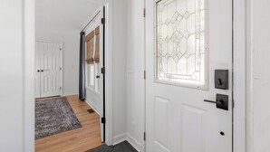 Eine weiße Tür mit Fensterglas, einem Türknauf und einem kleinen Fenster darüber.