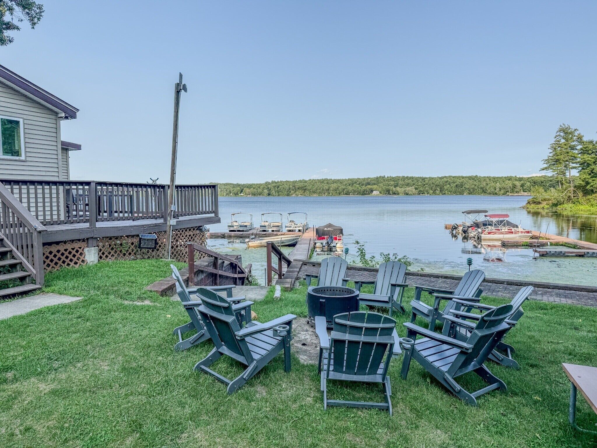 A lakeside deck with outdoor seating and a dock with boats.