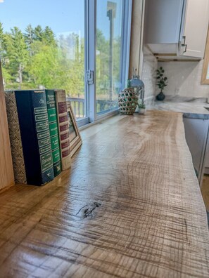 A wooden table with books, a window, and a plant.