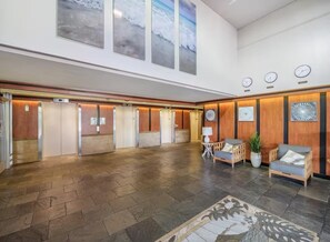 Eine geräumige Lobby mit Fischgrätparkett, Holzvertäfelung und einer Rezeption mit Pflanze und Lampe.