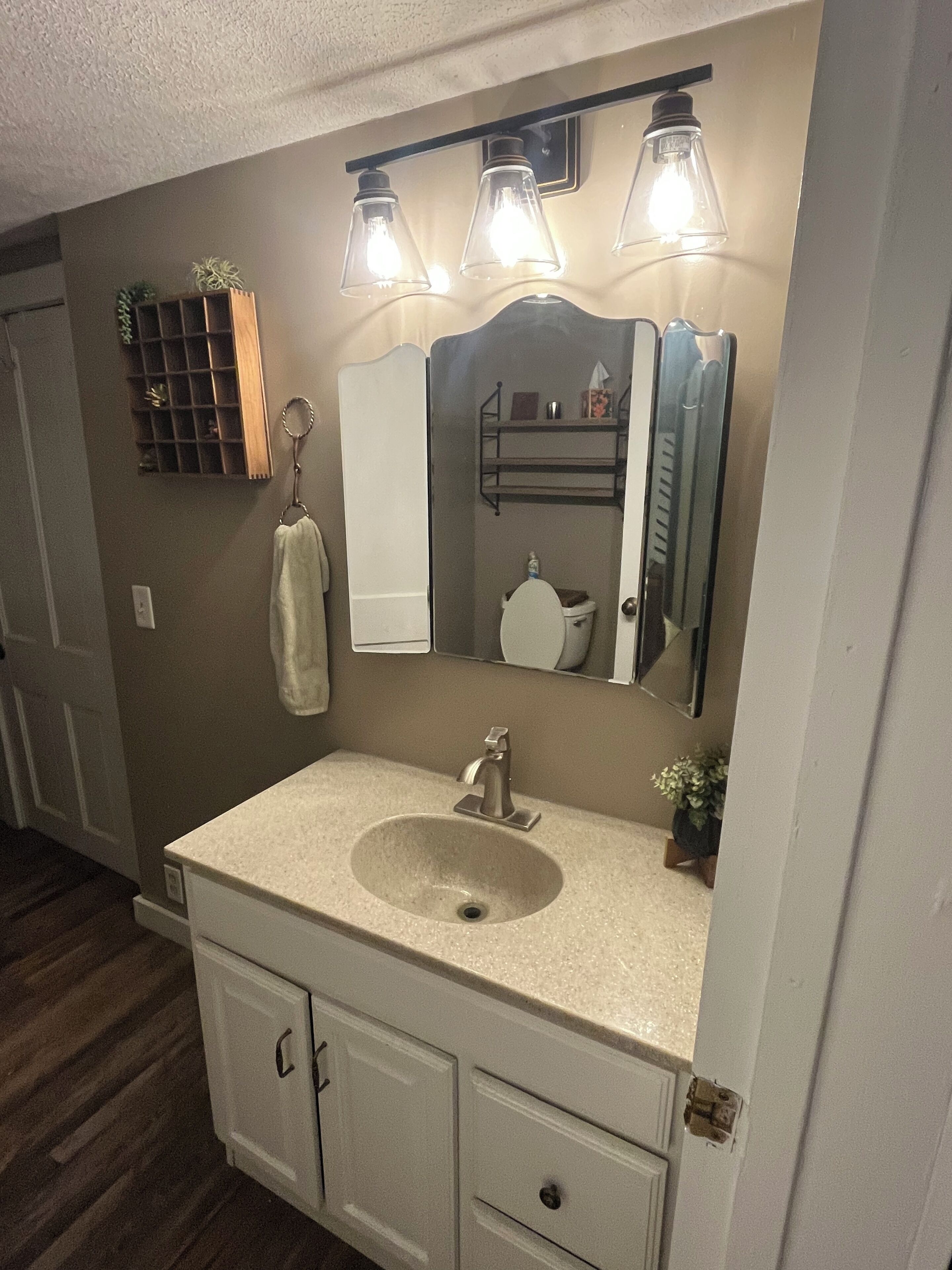 A bathroom with a sink, mirror, towel rack, and a shelf with toiletries.