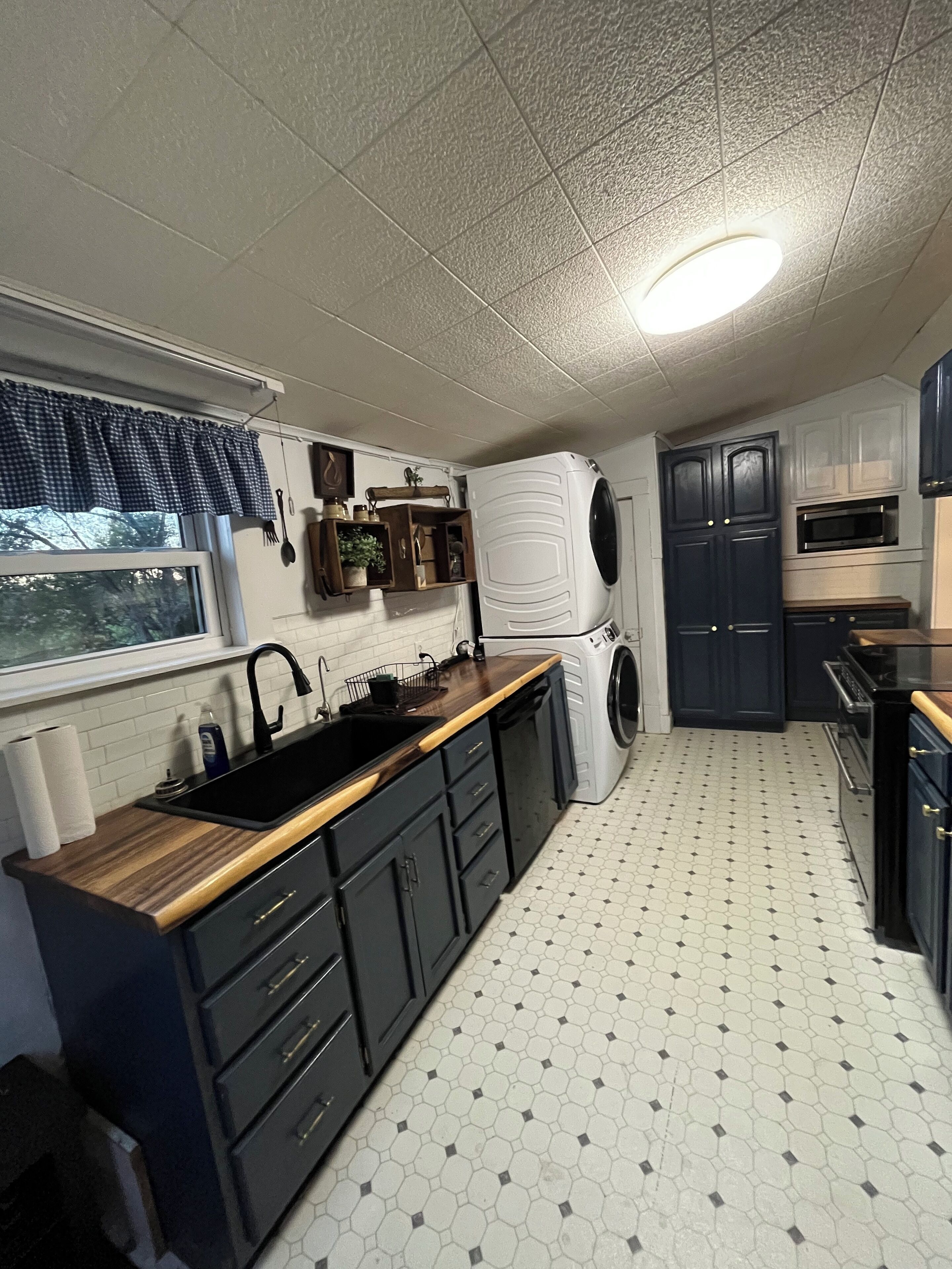 A compact kitchen with a sink, stove, microwave, and a washing machine.