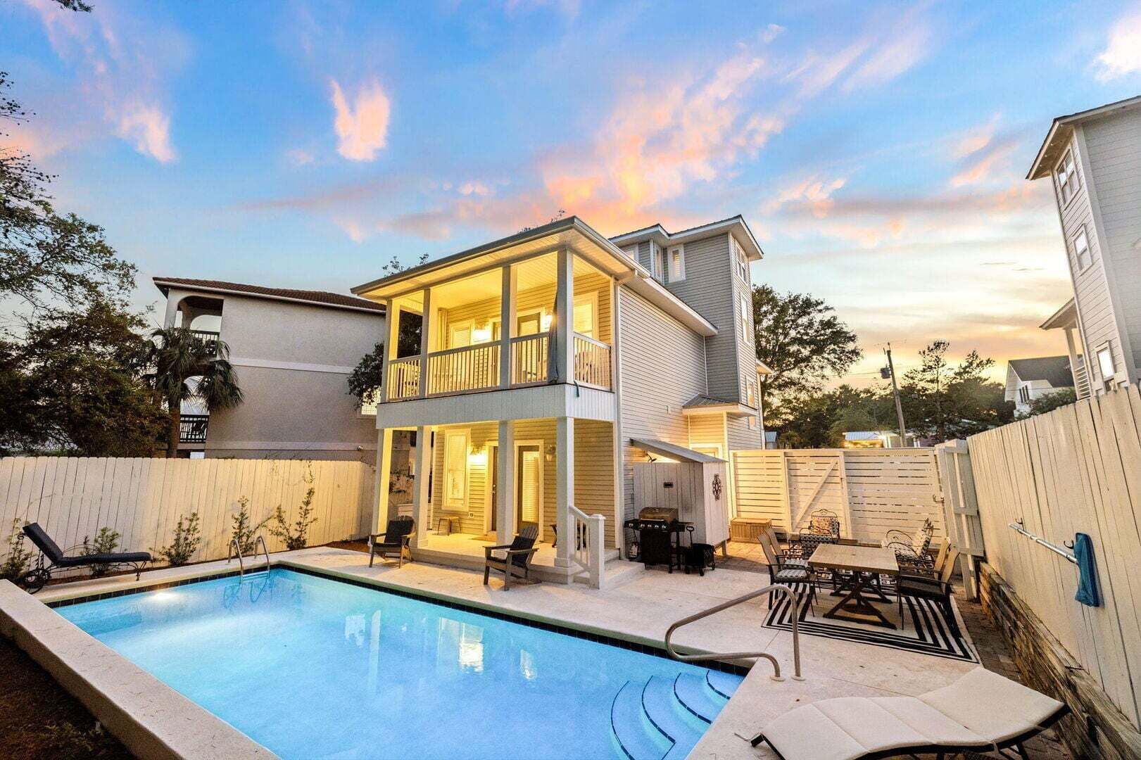 A two-story house with a pool, outdoor seating, and a fenced backyard.