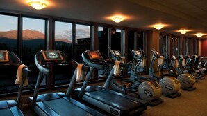 A gym with treadmills and elliptical machines, large windows with a mountain view, and exercise equipment with control panels. - Ski In/Ski Out Master at Grand Lodge on Peak 7 (Breckenridge)