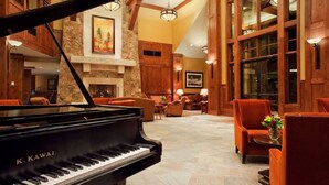 A grand lobby with a grand piano, wooden paneling, stone fireplace, and comfortable seating areas. - Ski In/Ski Out Master at Grand Lodge on Peak 7 (Breckenridge)