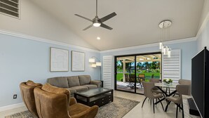 Una sala de estar espaciosa con ventilador de techo, un ventanal grande y un comedor con sillas y mesa.