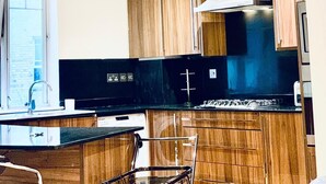 A modern kitchen with wooden cabinets, a black countertop, and stainless steel appliances. - Unpack and Unwind in Our Cozy London Retreat (London)