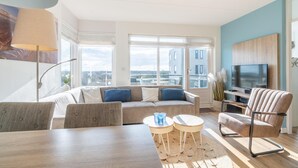 Un salon moderne avec un canapé, un téléviseur et un coin repas.