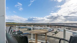 Un balcon donnant sur un parking et un ciel nuageux.