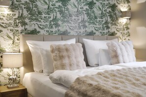 A neatly made bed with white linens and fluffy pillows, a bedside lamp, and a wall with a nature-themed wallpaper. - Alpenchalet Berggold - Holiday Home With Panoramic Views (Tulfes)
