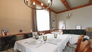 Uma área de refeições com uma mesa posta para dois, cadeiras de madeira e um candelabro.