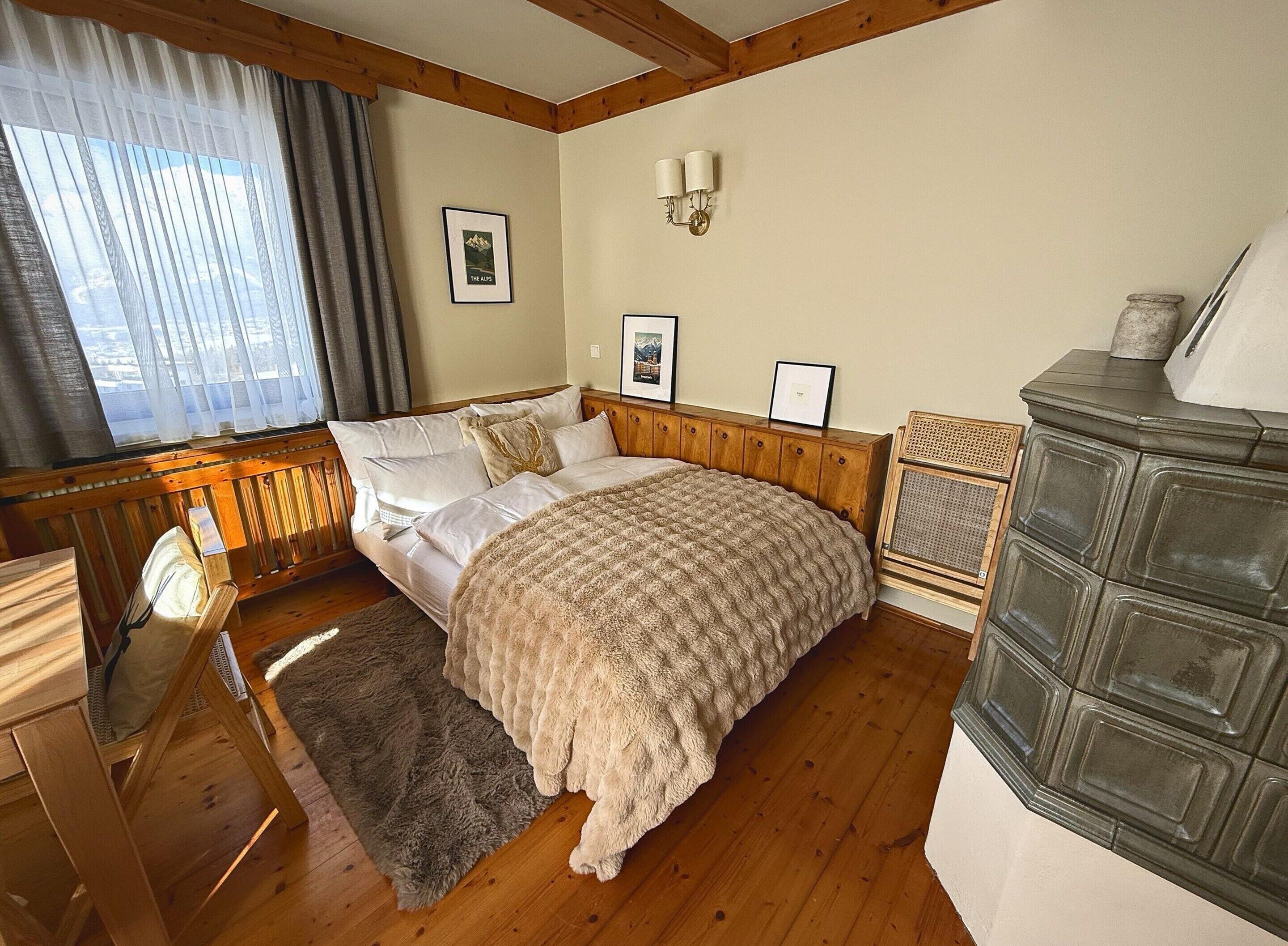 A bedroom with a wooden headboard, a large bed with a textured blanket, a wooden dresser, and a fireplace.
