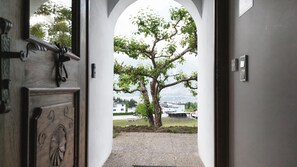 An arched doorway leading to a view of a tree and buildings in the distance. - Alpenchalet Berggold - Holiday Home With Panoramic Views (Tulfes)